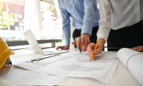 Team architect meeting and consult with blueprint and computer in architecture office.